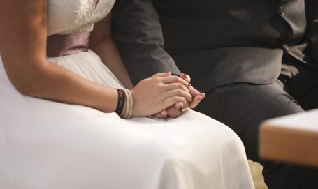 Händchen haltendes Paar in Hochzeitskleidung. Elegante und intime Geste.