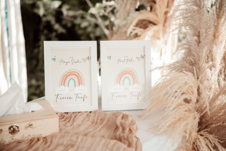 Zwei Karten mit Regenbogenmotiven neben dekorativen Trockenblumen.