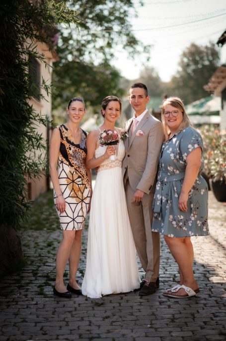 Hochzeitsfeier mit vier Personen, zwei in elegante Kleidung, zwei in festlichen Outfits.