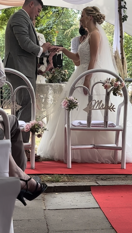Hochzeit mit Trauung im Freien, Braut in Weiß, Gäste in eleganter Kleidung.