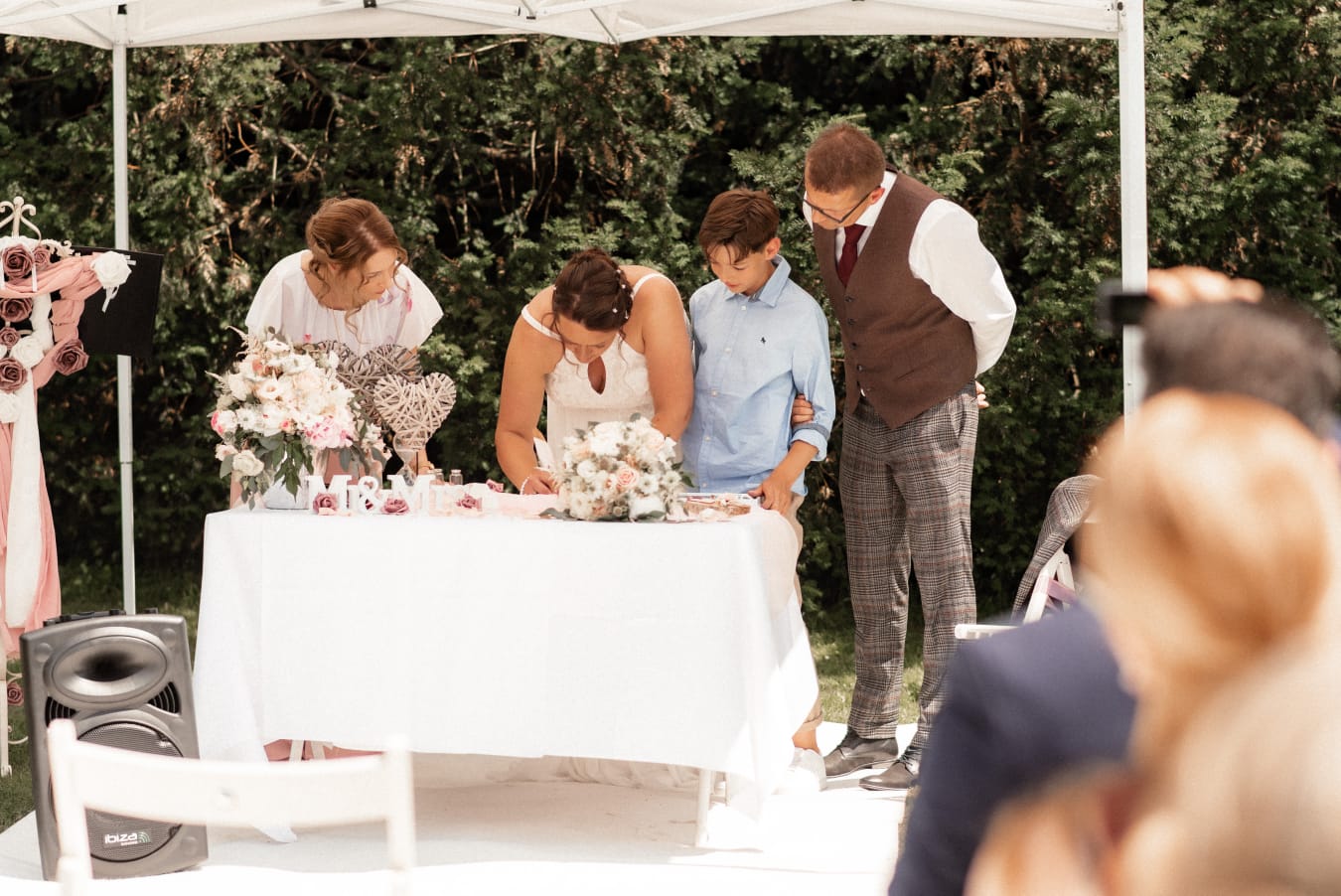 Braut und Gäste unterschreiben an einem dekorierten Tisch bei einer Hochzeit.