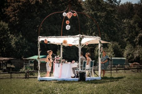 Hochzeitszeremonie unter einem dekorierten Pavillon im Freien mit Gästen.