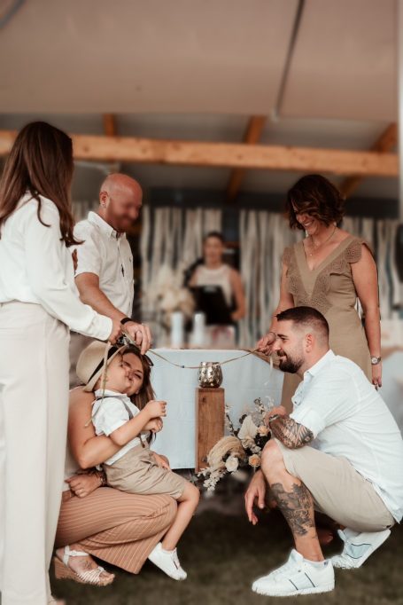 Familie feiert zusammen, ein Kind sitzt auf dem Boden und interagiert mit den Erwachsenen.