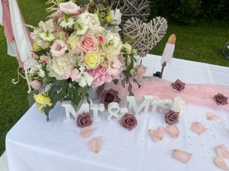 Blumenarrangement und Dekoration mit "Mr & Mrs" auf einem Tisch.