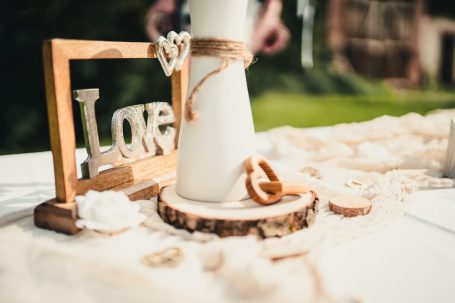 Dekoration mit dem Schriftzug "Love", Holzscheiben und einer weißen Vase auf einem Tisch.