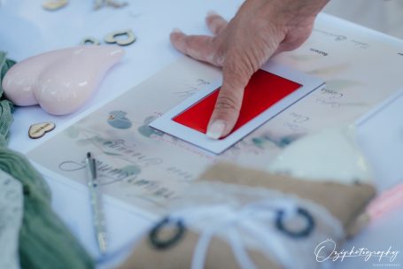 Eine Hand drückt auf eine rote Karte auf einem Tisch mit verschiedenen Dekorationselementen.